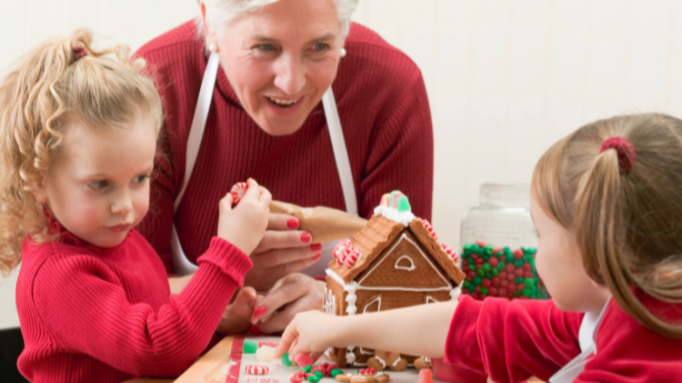 Stock photo of a grandparent helping young children decorate a gingerbread house. Stock photo of a grandparent helping young children decorate a gingerbread house.